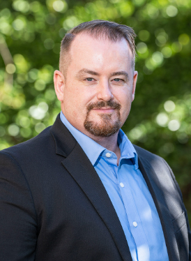 This is my professional headshot.  It is a picture of me in a blue suit, standing in front of green topiary background.